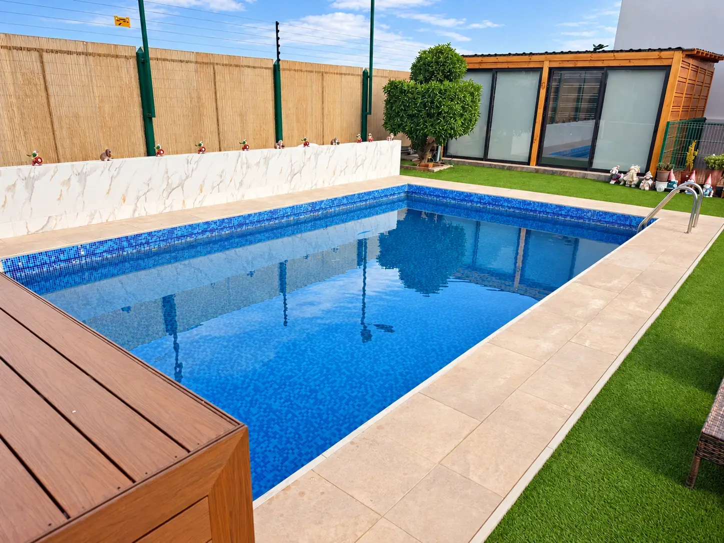Piscina rodeada de una terraza y jardín para disfrutar al aire libre