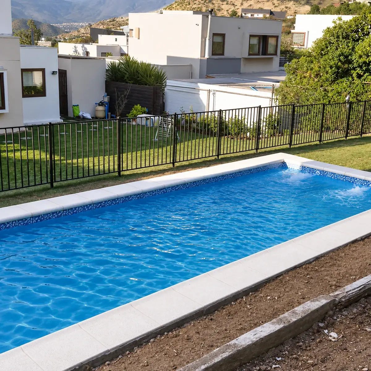 Piscina rectangular con borde claro, cierre de seguridad y vista hacia las casas y cerros