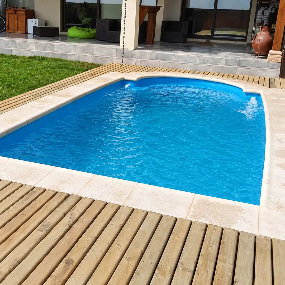 Piscina de extremo redondeado con borde de piedra y terraza de madera