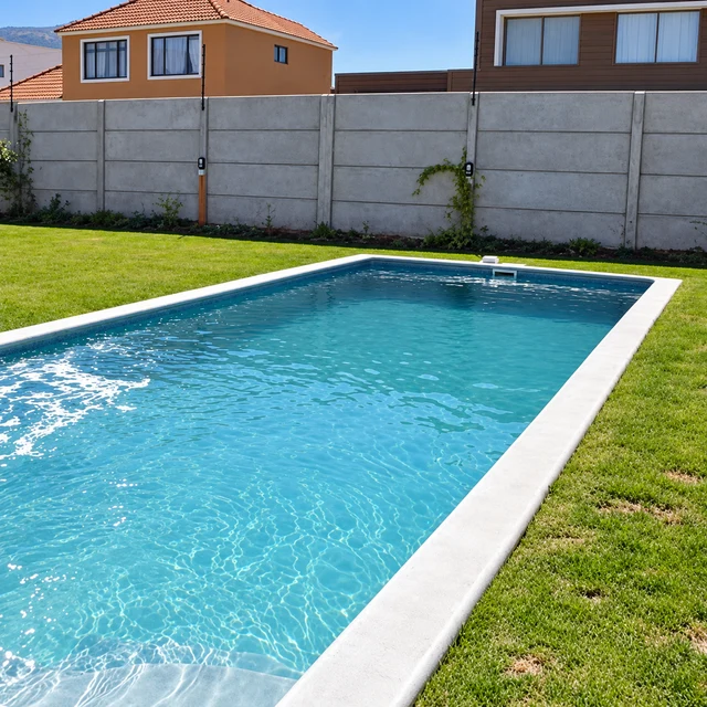 Piscina rectangular con borde blanco rodeada de césped en un jardín residencial